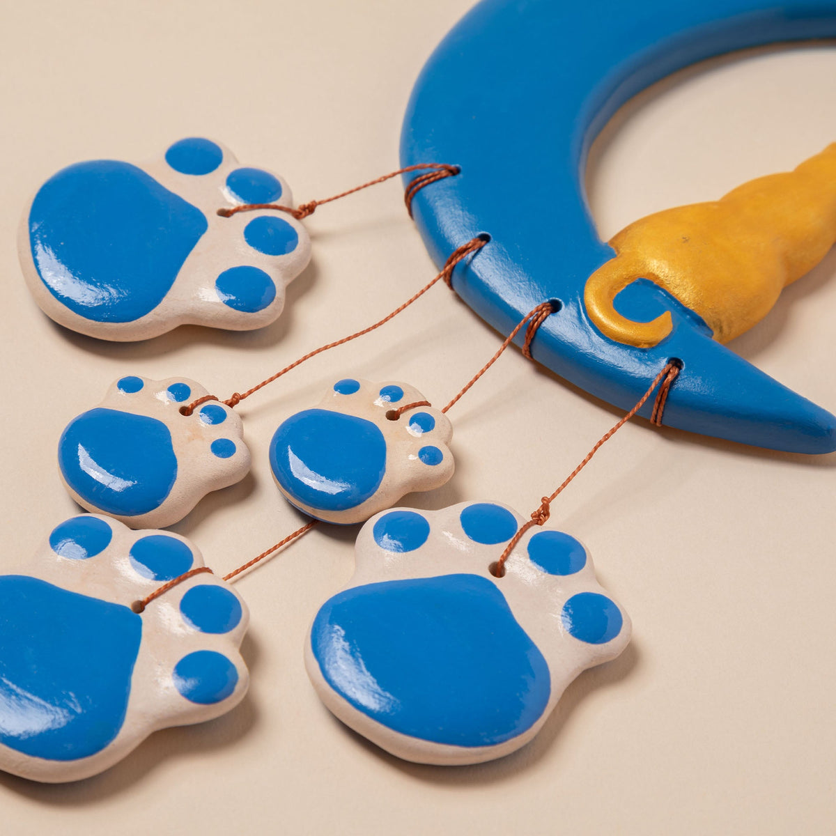 Close-up of blue ceramic paw charms and strings on a blue crescent moon wind chime