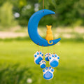 Ceramic cat paw wind chime with blue crescent moon and dangling blue paw ornaments outdoors