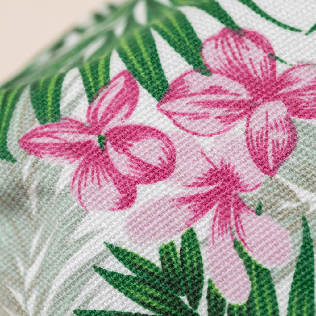 Tropical floral fabric with pink hibiscus blooms and green palm leaves