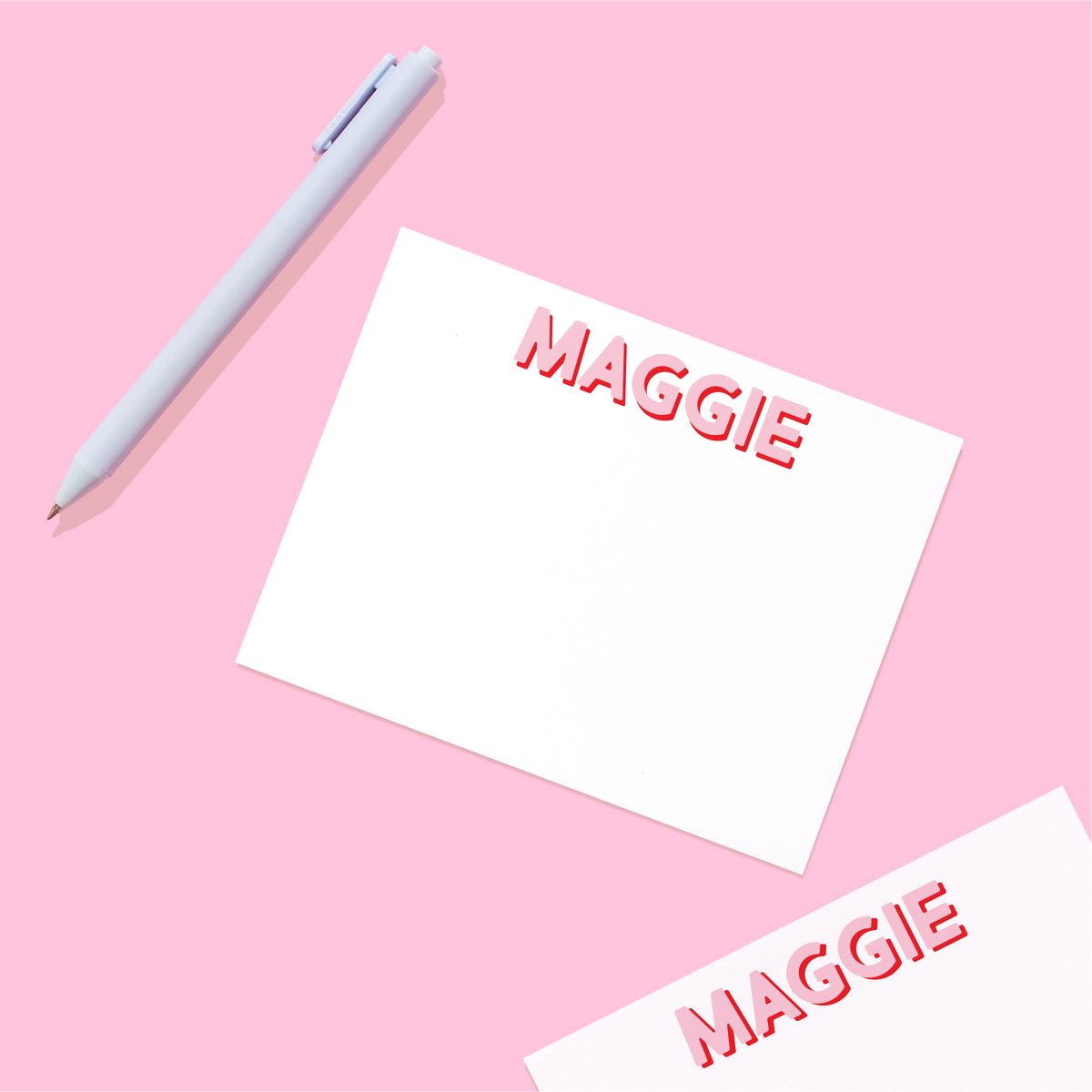 Personalized stationery name card with red “MAGGIE” text; white card and gray pen