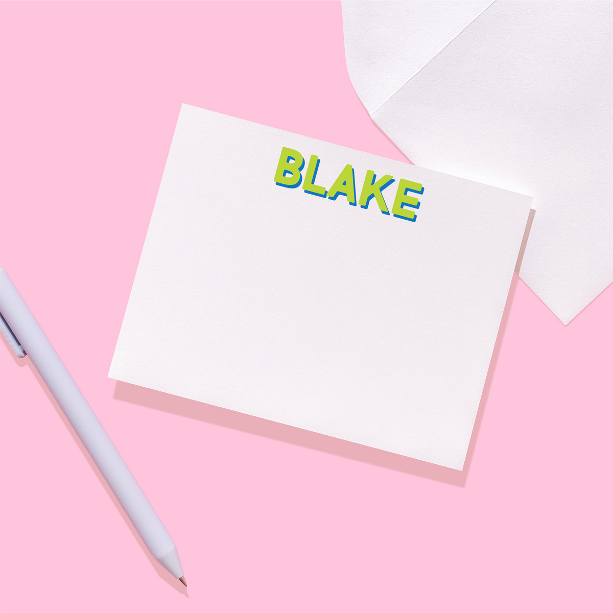 Close-up personalized stationery name card with green “BLAKE” text; gray pen