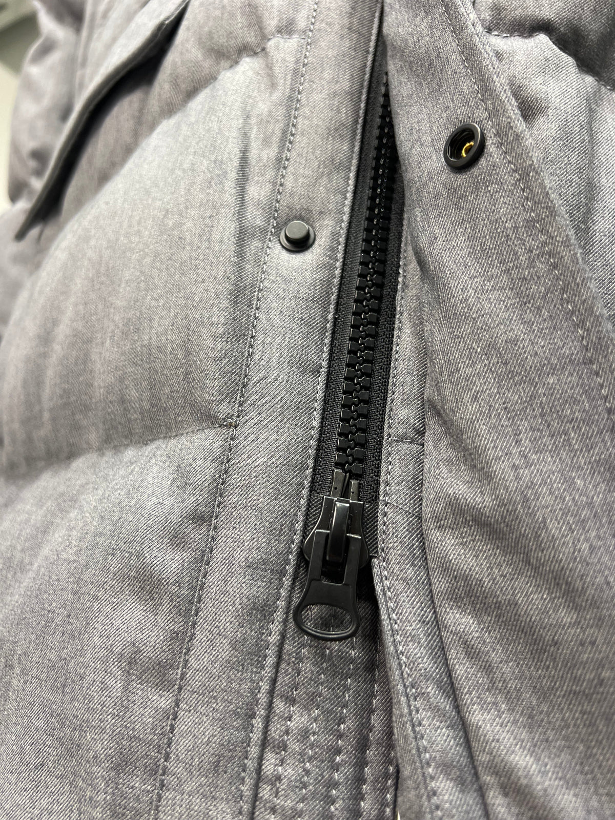 Close-up of grey coat zipper track with snap placket and round buttons