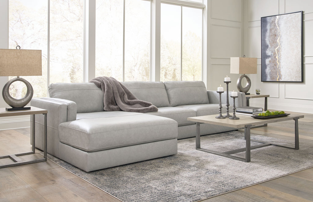 Light gray sectional sofa with corner chaise, tufted seat cushions, and throw blanket