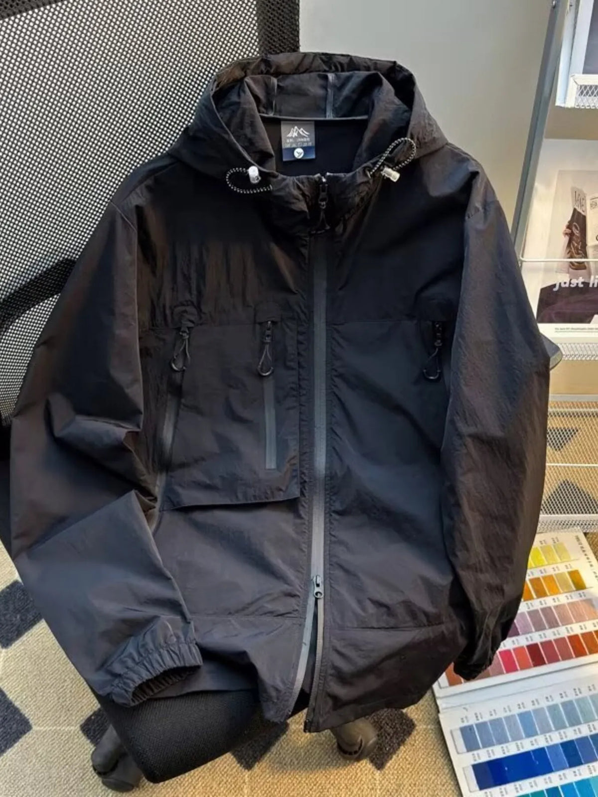 Lightweight hooded windbreaker jacket in dark gray with full zip and utility pockets