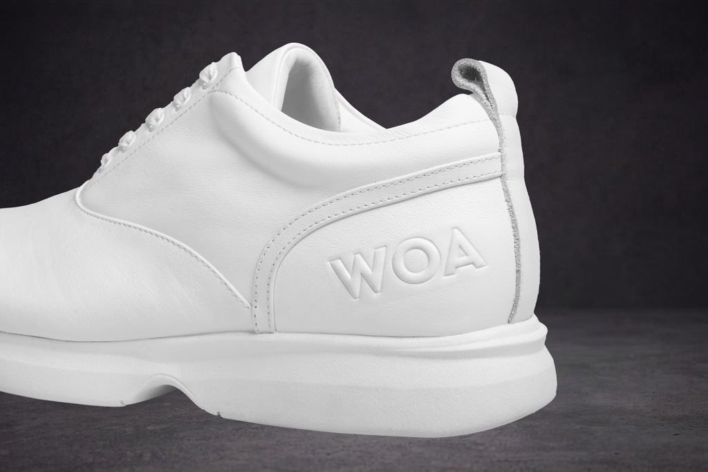 Close-up of white sneaker side with WOA logo and cushioned sole