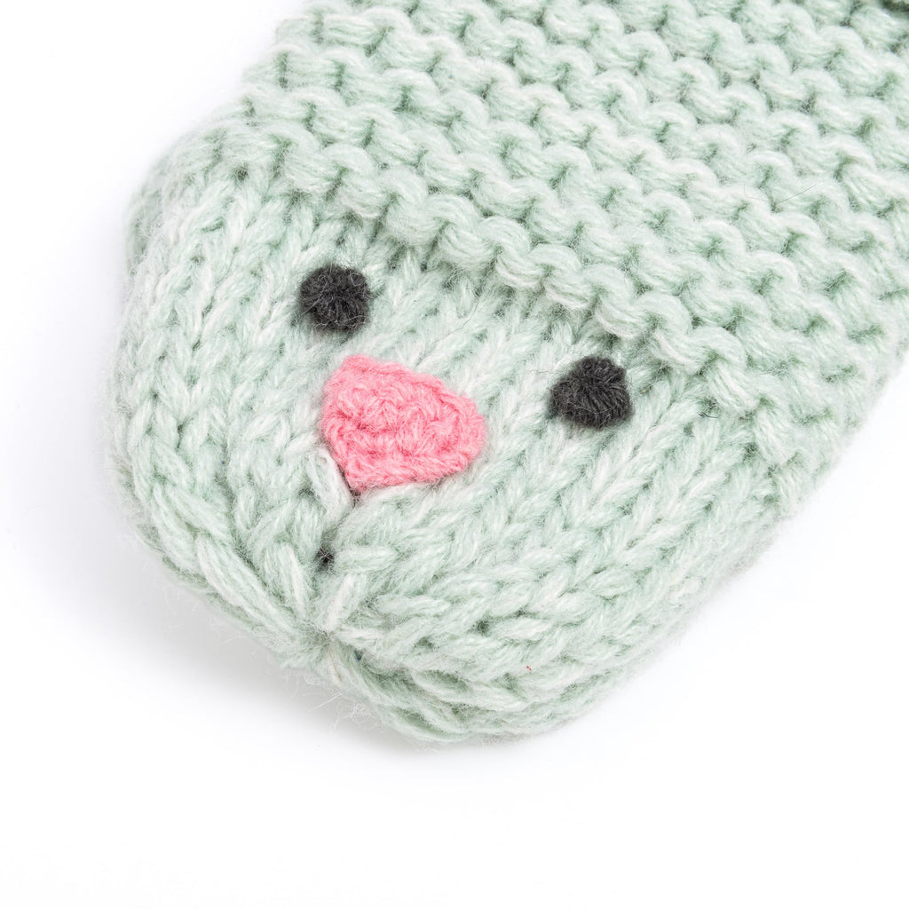 Mint green knitted chick mitten close-up with embroidered face and stitched beak