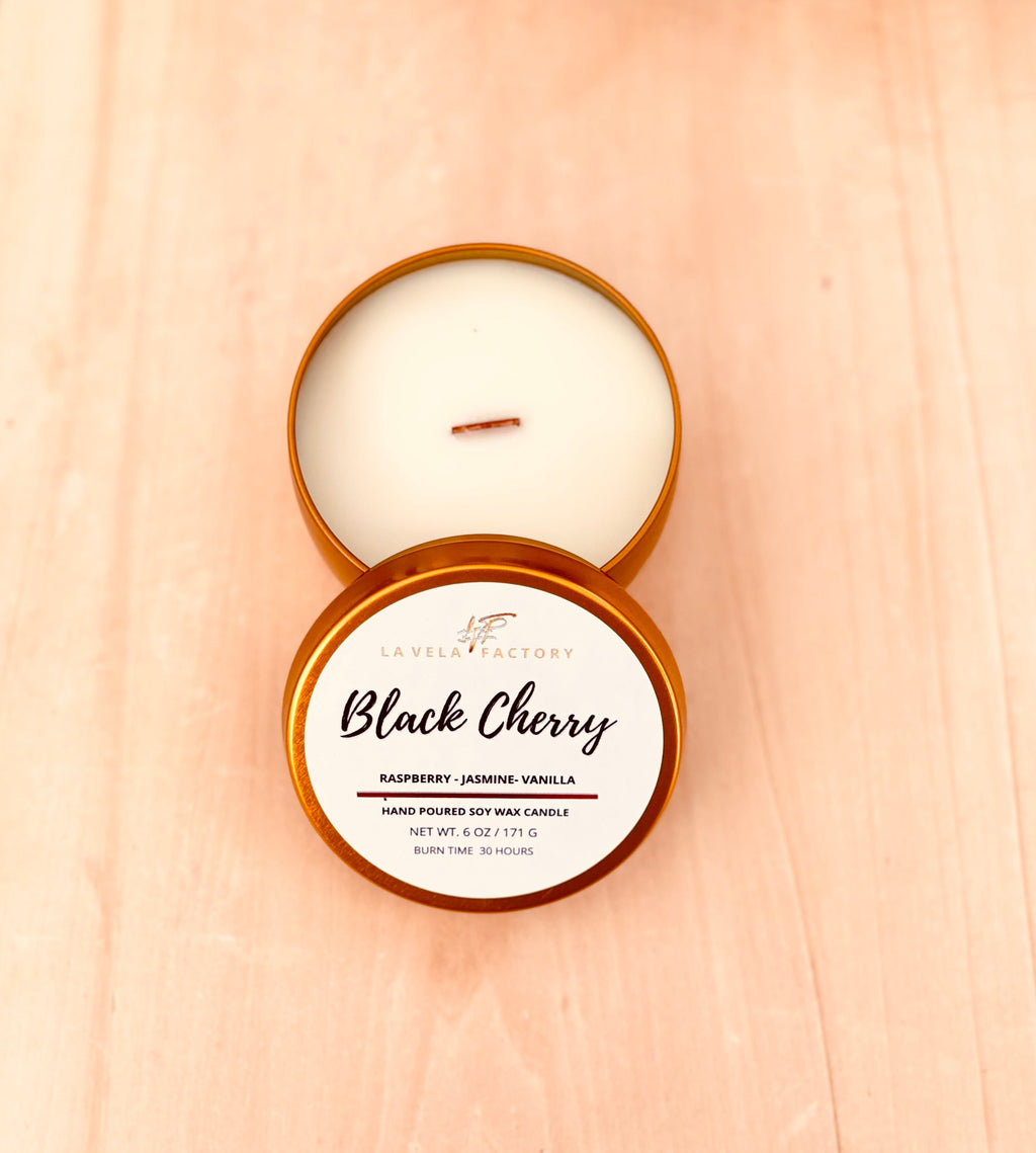 Wood-wick candle with white wax; amber tin labeled Black Cherry.