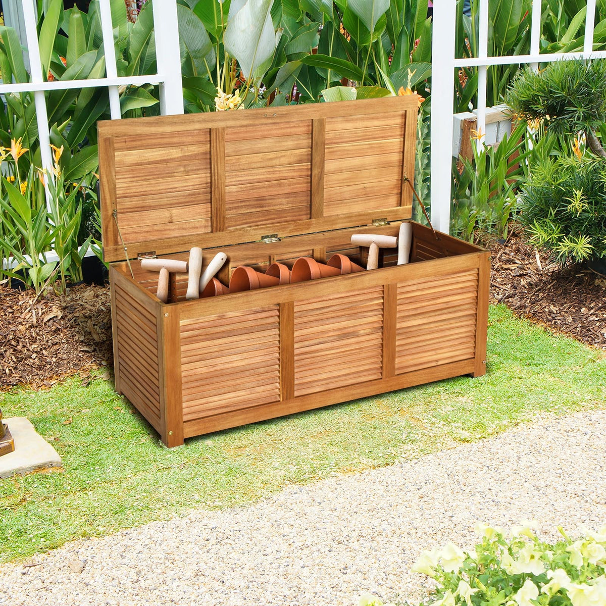 Wood storage bench with open top showing tools and gardening items, in yard