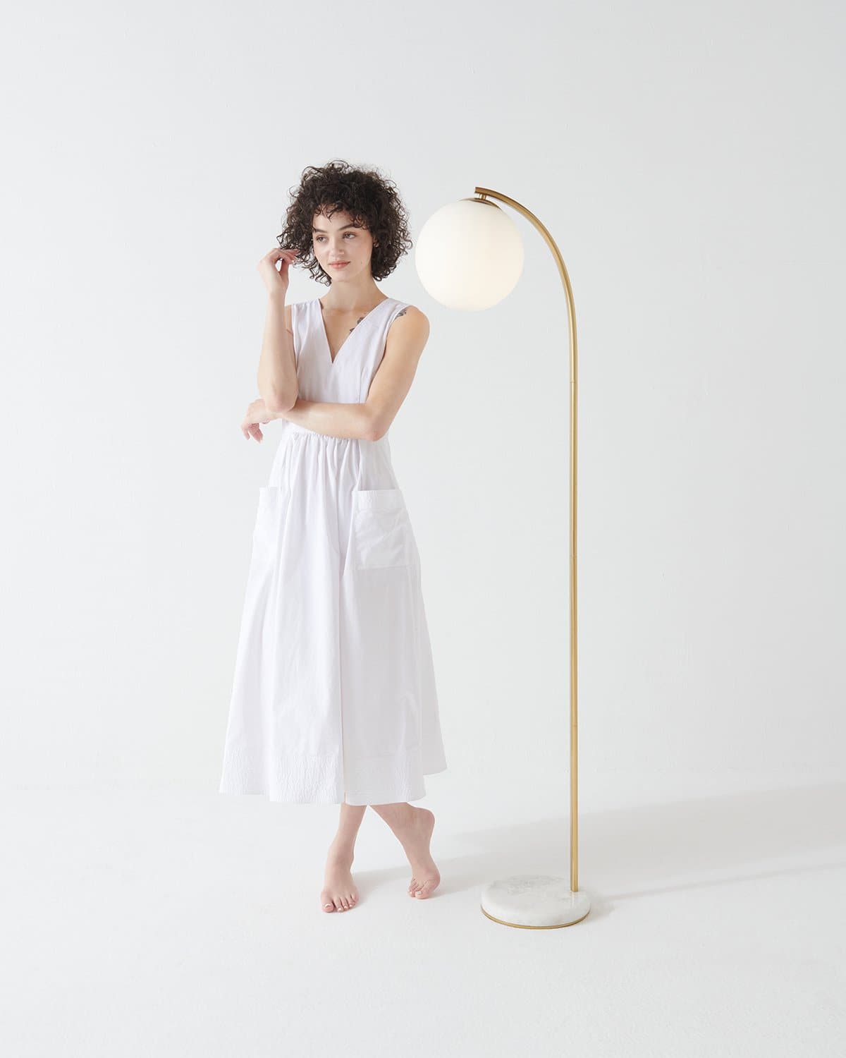 Gold arched floor lamp with round white globe shade, standing on base