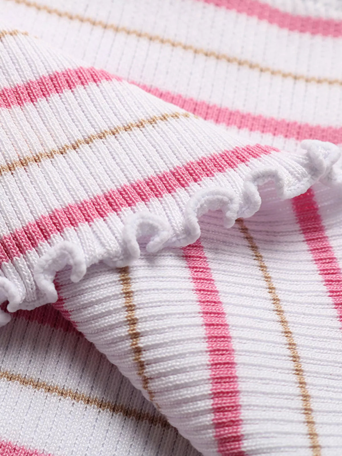 Close-up knit fabric of pink, white, and tan stripes with white ruffle edge
