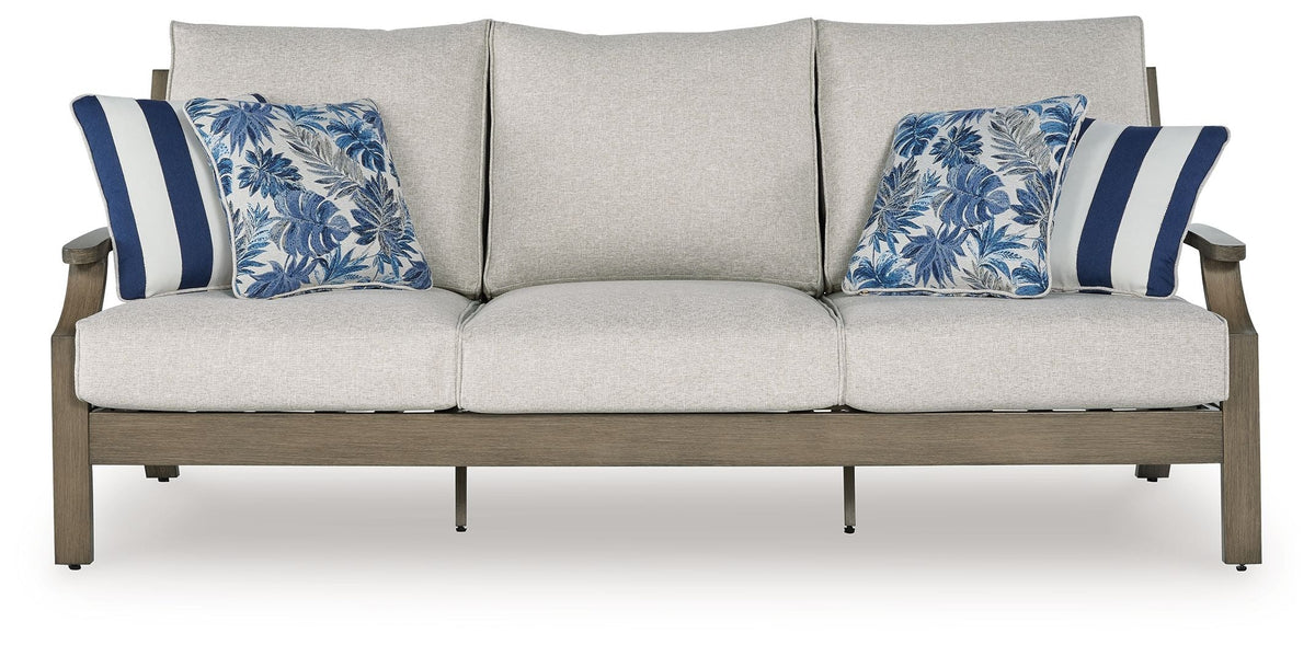 Outdoor sofa with three light gray seat cushions and two blue patterned accent pillows