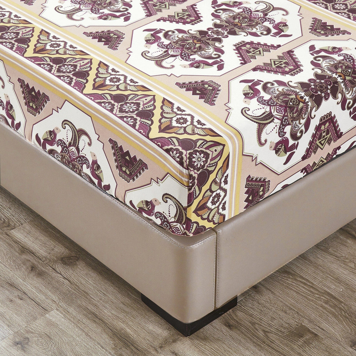 Close-up of fitted sheet corner with ornate kilim pattern in burgundy, cream, and gold