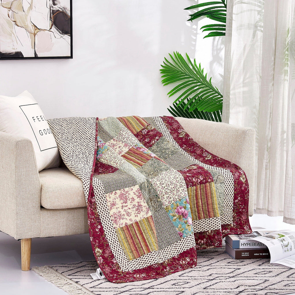 Folded patchwork quilted throw blanket with beige, burgundy, and multicolor floral panels.