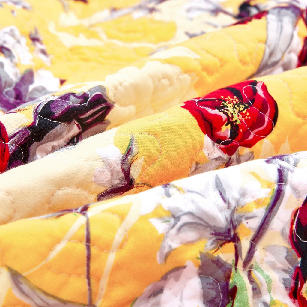 Close-up of yellow quilted blanket texture with floral and bird print
