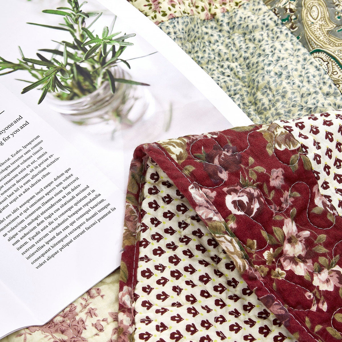 Close-up of quilted throw fabric: burgundy floral with beige mini patterns and stripes.
