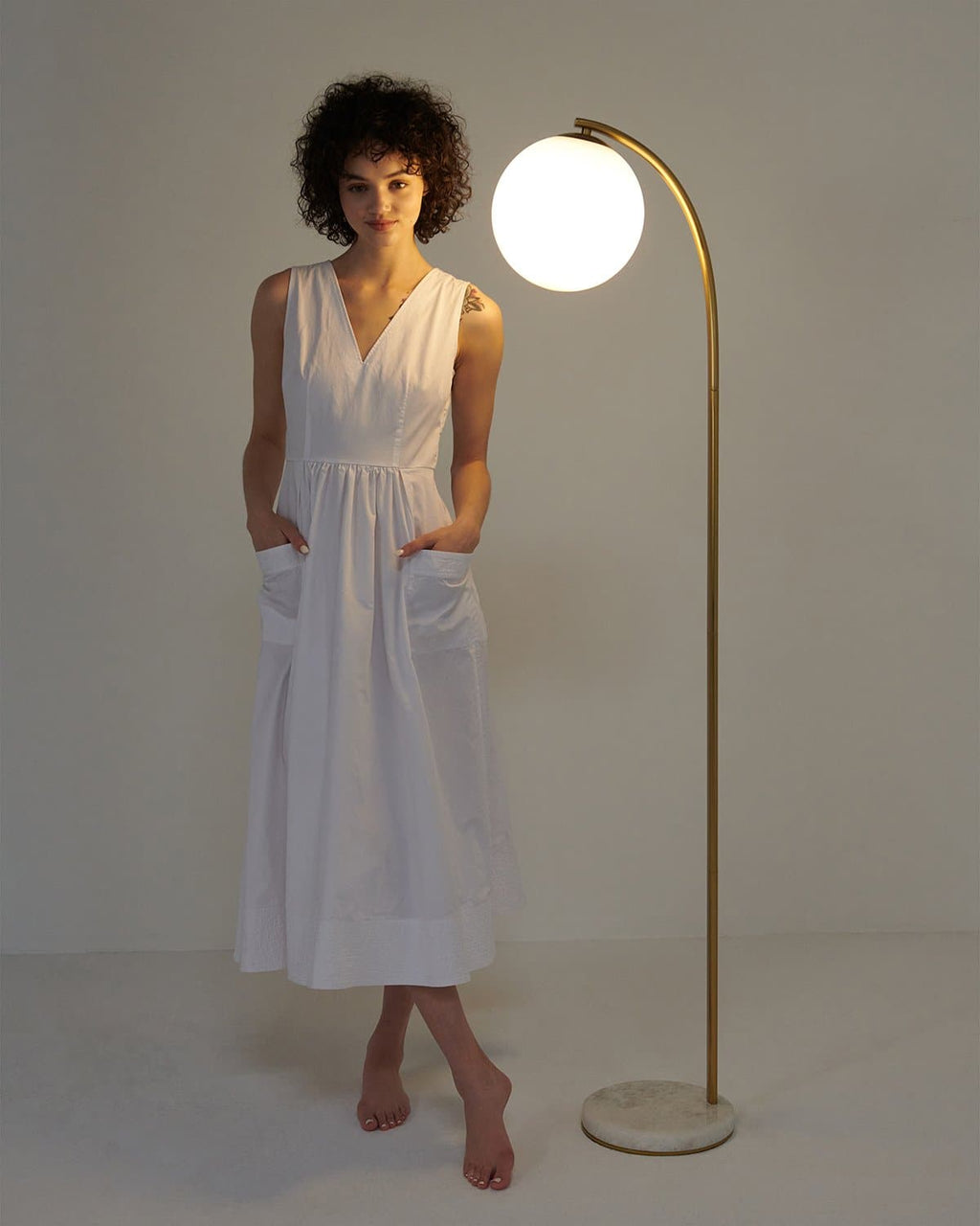 Gold curved floor lamp with round white globe shade