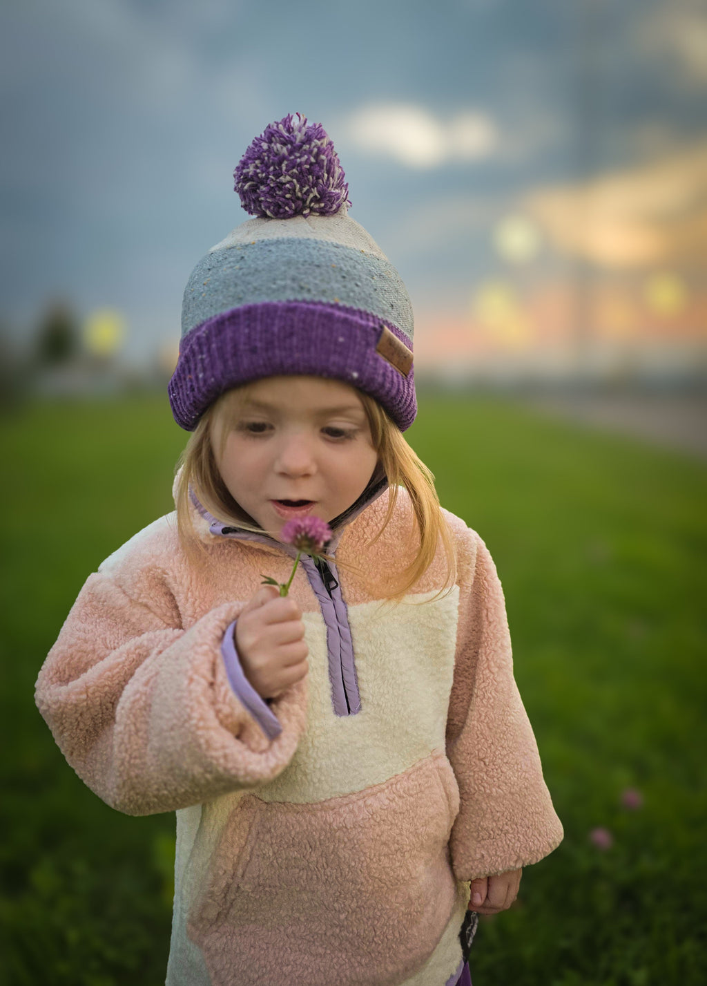 Child wearing purple knit puff beanie with pompom
