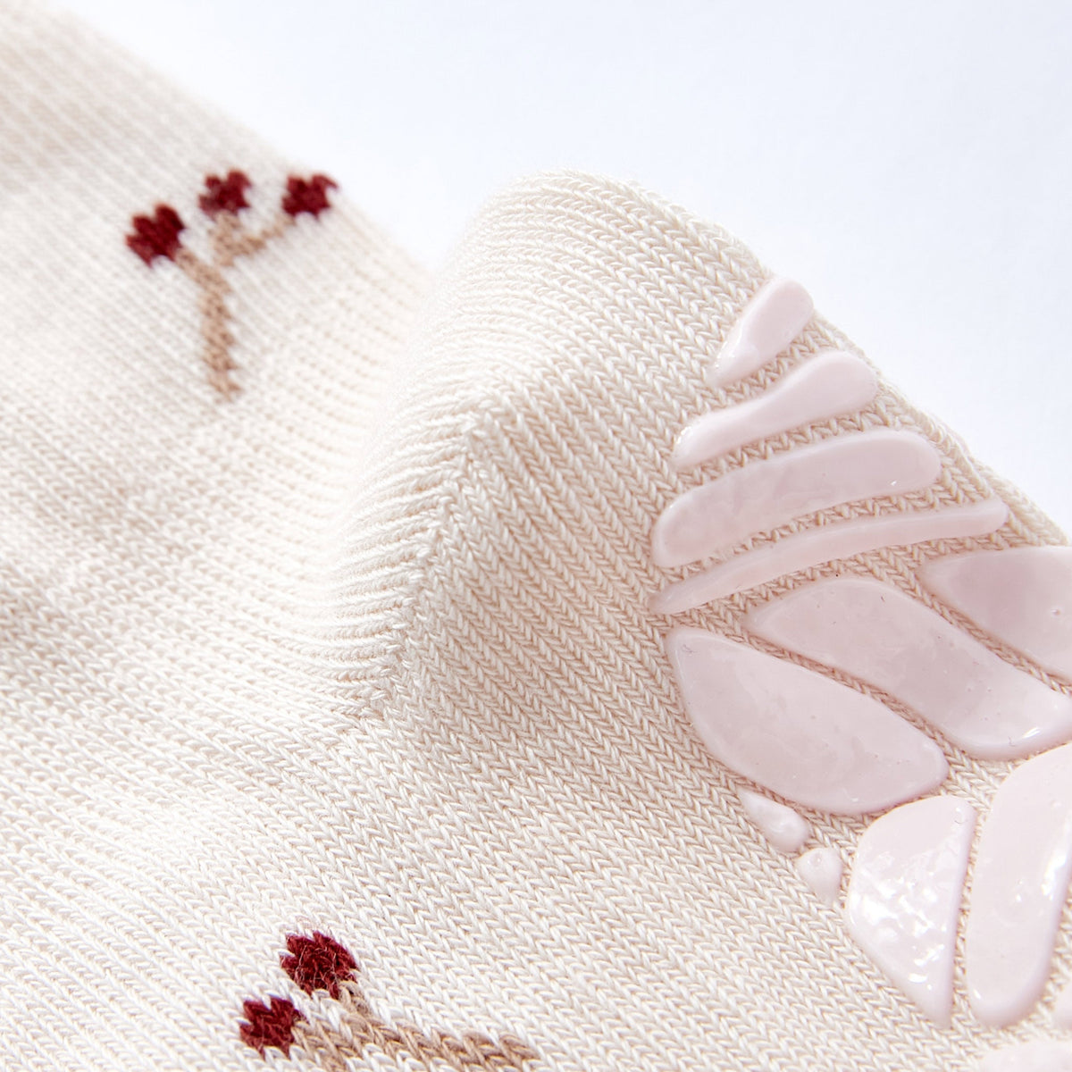 Cream baby sock with embroidered red motifs and textured non-slip sole