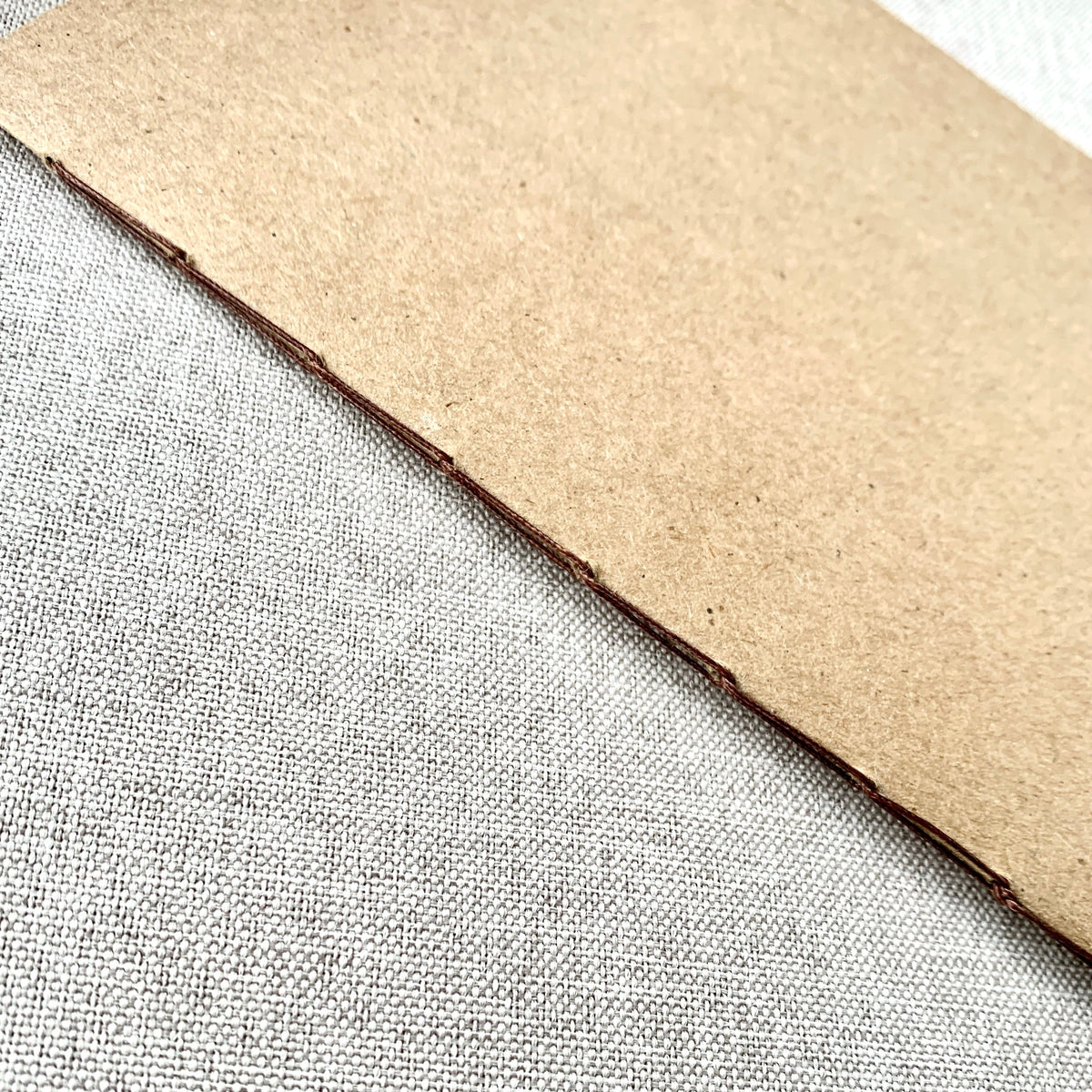 Kraft notebook insert corner with stitched binding edge in dark brown