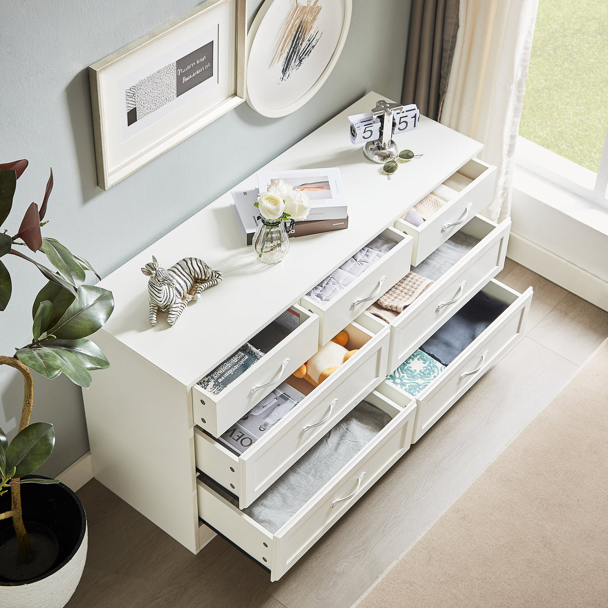 White dresser chest with open drawers and stored items, chrome metal pulls