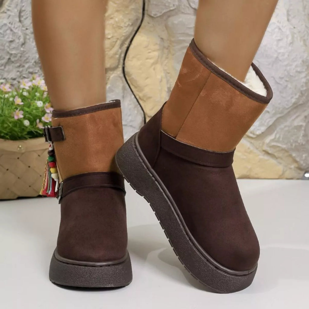 Two-tone ankle boots with buckled strap and tassel accents on a stacked sole.