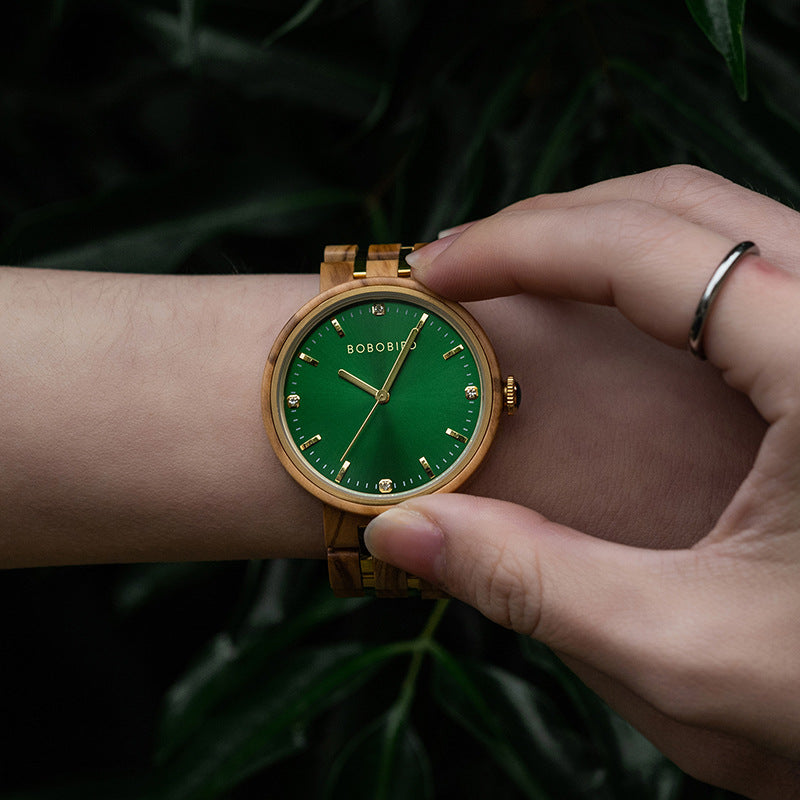 Womens quartz watch with green dial and gold case on light tan wood-style link band