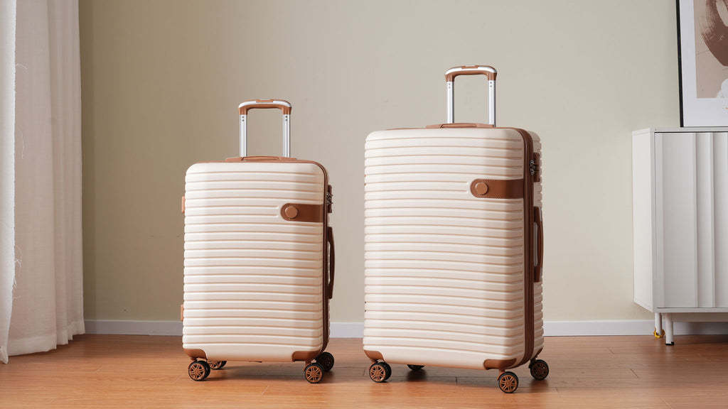 Two cream hard-shell suitcases with telescoping handles and spinner wheels
