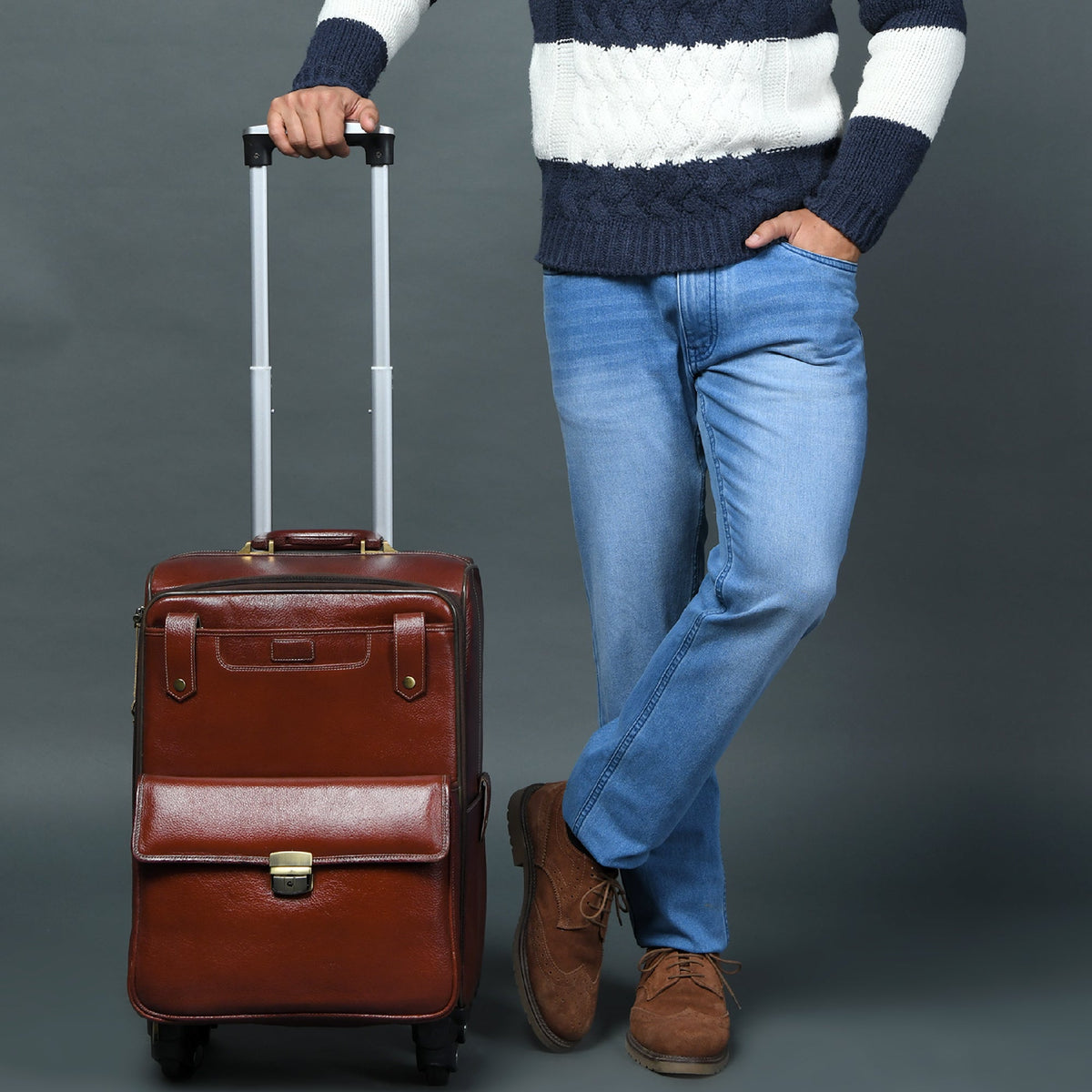 Brown leather carry-on trolley bag held upright with retractable handle and four caster wheels