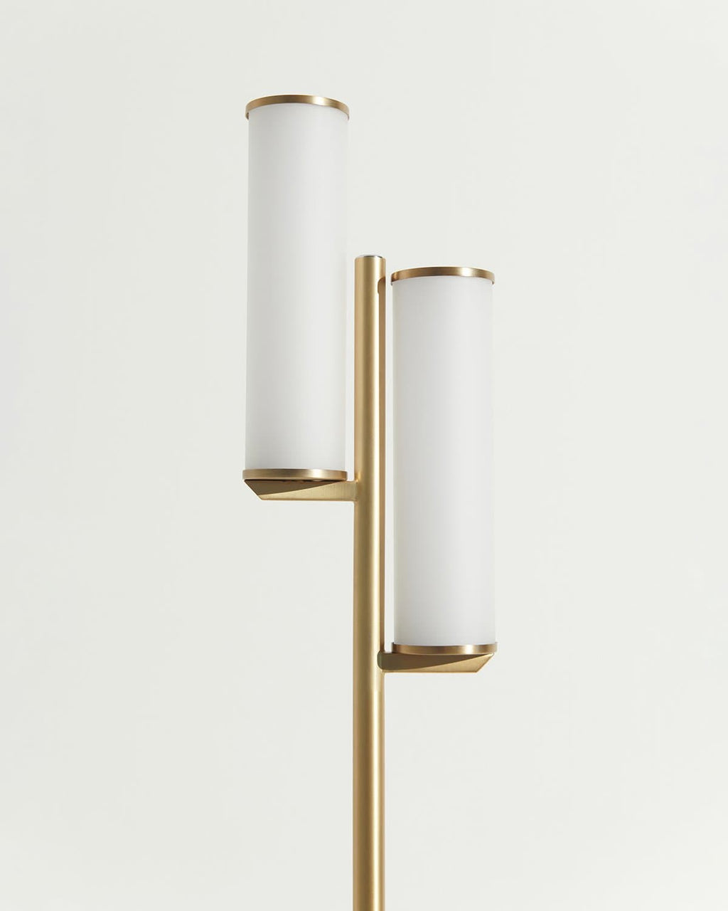 Brass floor lamp close-up showing two frosted glass cylinders