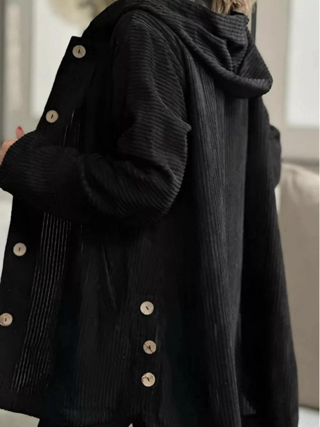 Black corduroy hooded button-up jacket, close side view showing buttons and sleeve texture