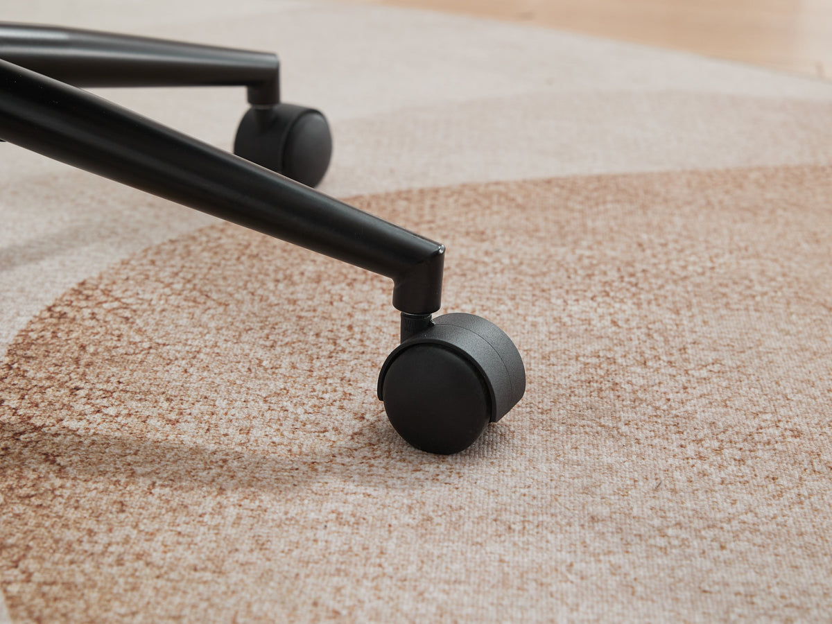 Black caster wheel of a grey upholstered office chair on carpet