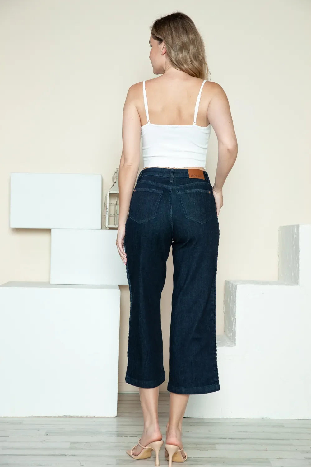 Dark wide-leg cropped jeans with side braid detail, back view