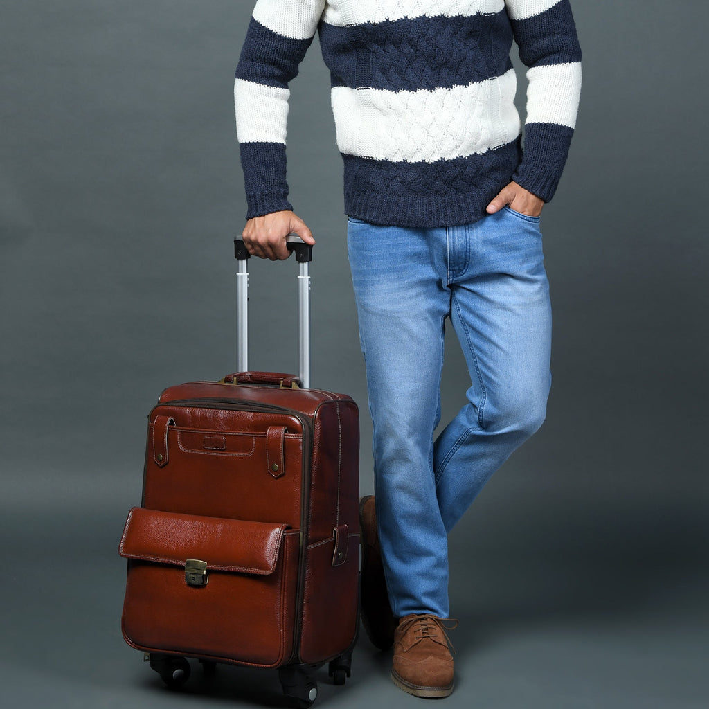 Brown leather carry-on trolley bag with front pocket and retractable handle held while walking