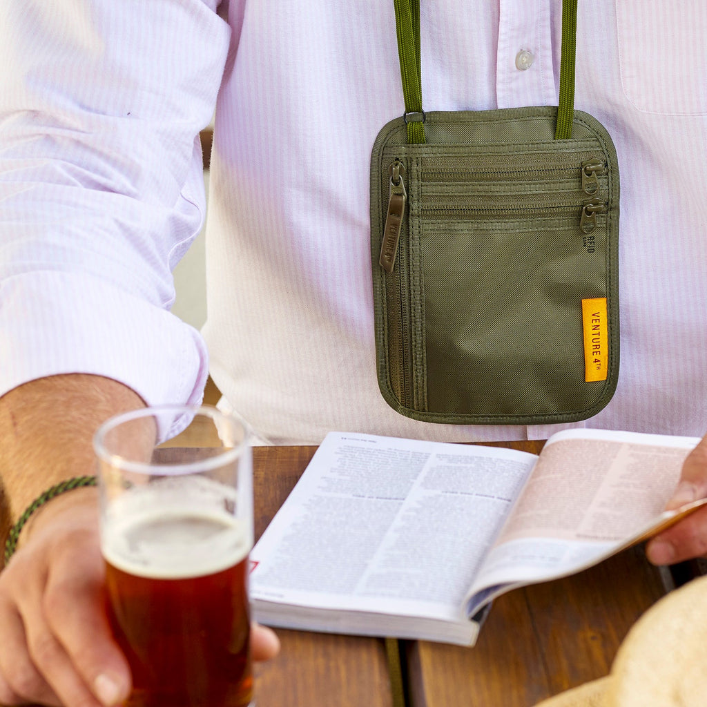 Green slim travel neck wallet with multiple zip pockets and adjustable neck strap.