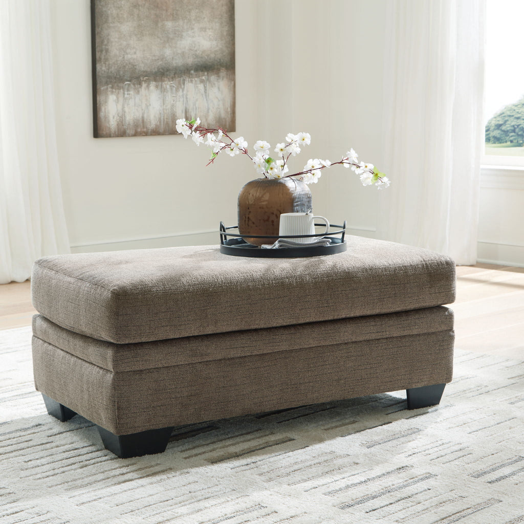 Stonemeade upholstered ottoman in textured light gray, with tapered legs