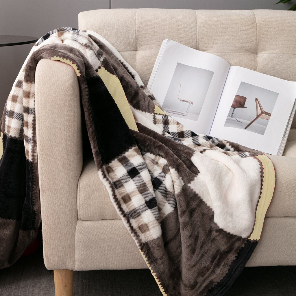 Plaid throw blanket over beige sofa arm with brown, cream, and navy patches