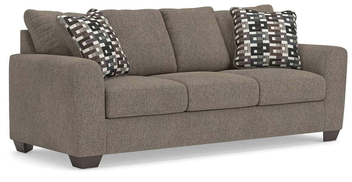 Beige upholstered sofa with three seat cushions and black-and-white geometric pillows