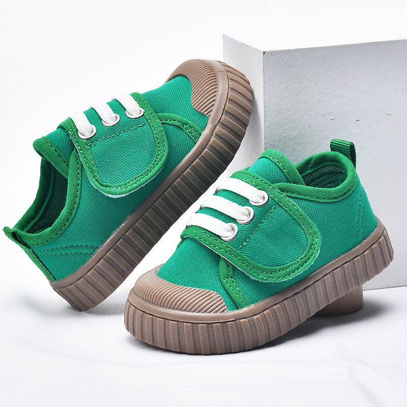 Green baby first-walker sneakers with brown sole and white lace-up straps