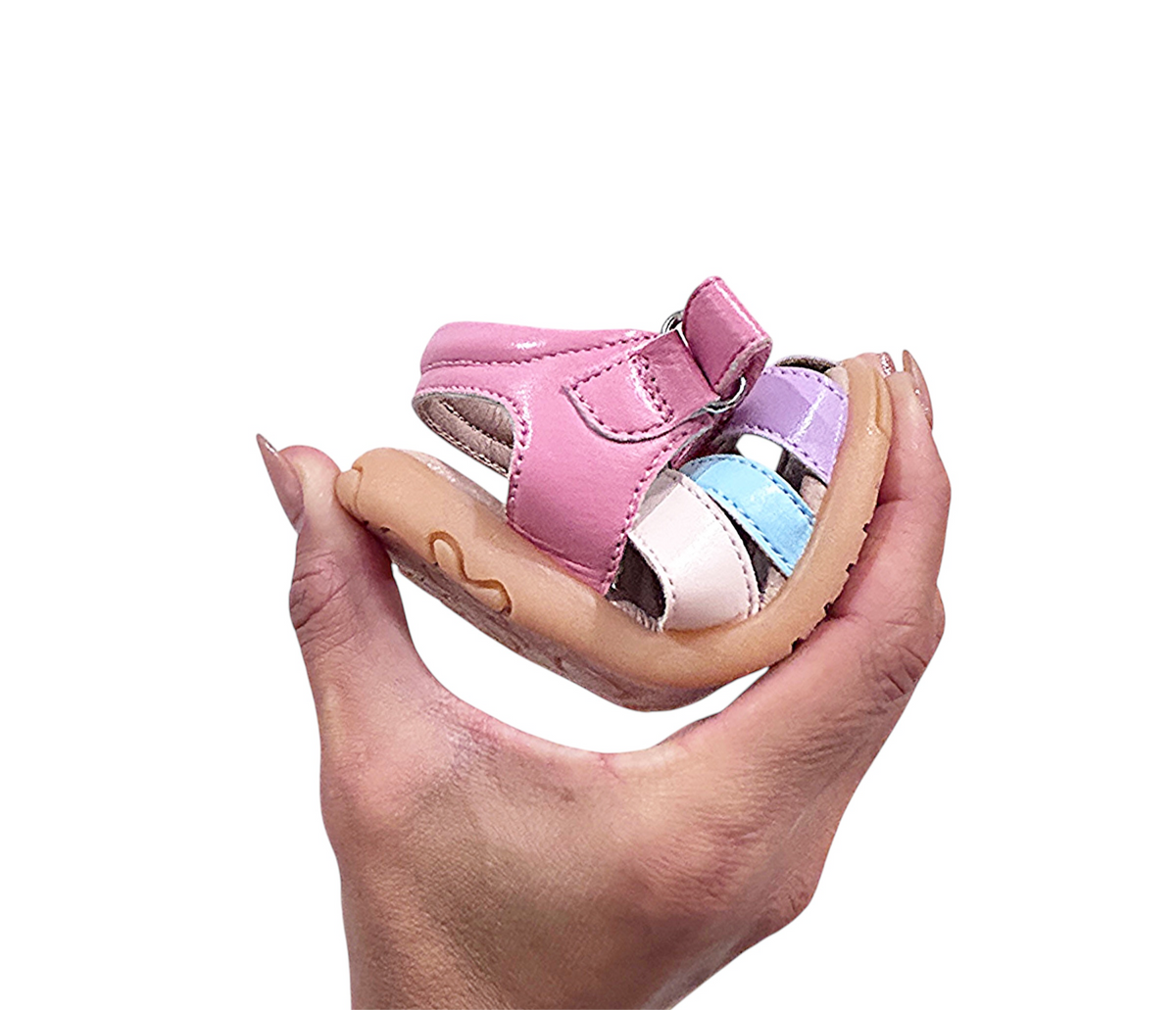 Kids closed-toe sandal held in hand, pink with beige and blue multi-strap design