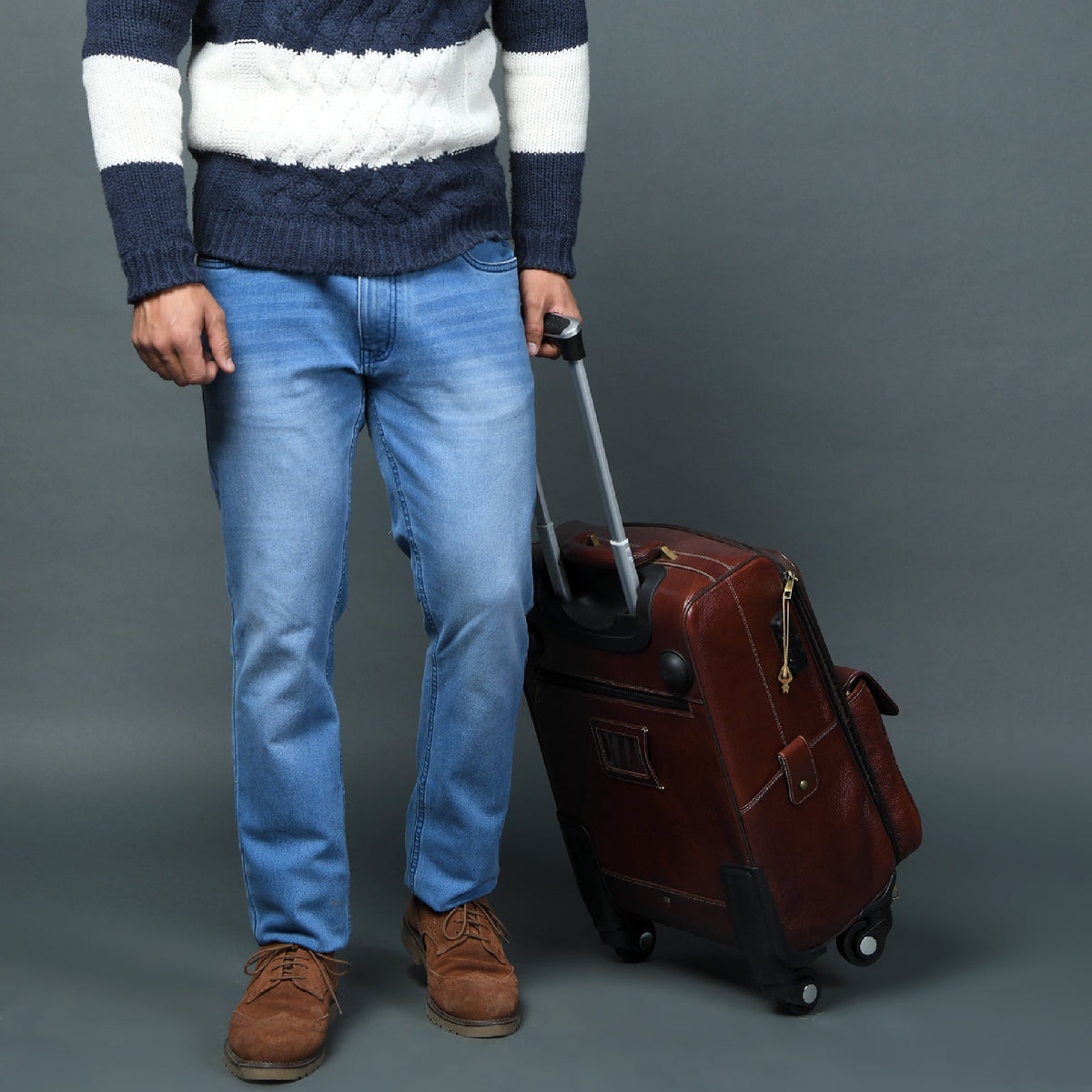 Brown leather carry-on trolley bag angled view with side panel details and caster wheels