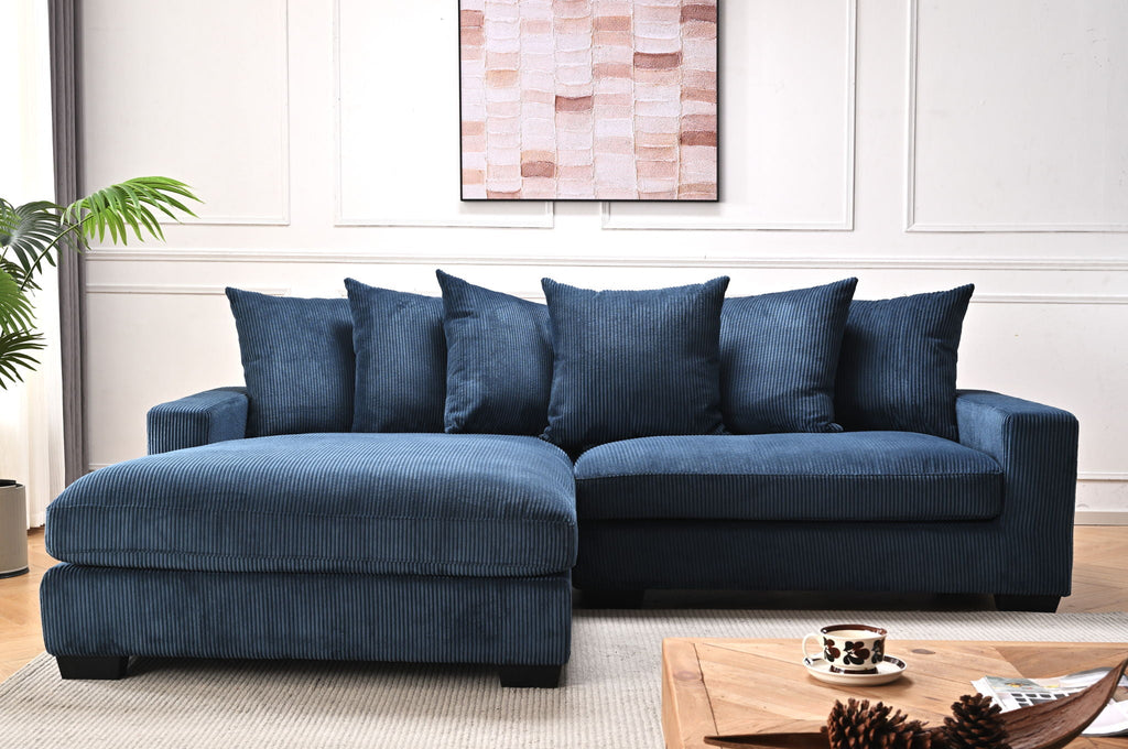 Blue L-shaped sectional sofa with chaise, multiple throw pillows and textured upholstery.