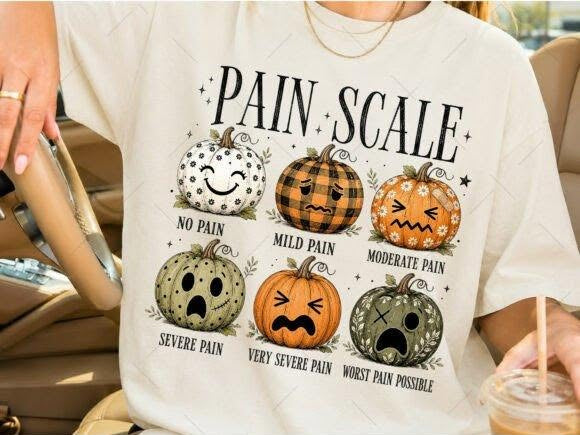 Cream graphic tee with pain scale pumpkins, including quotes like “No pain” and “Mild pain”