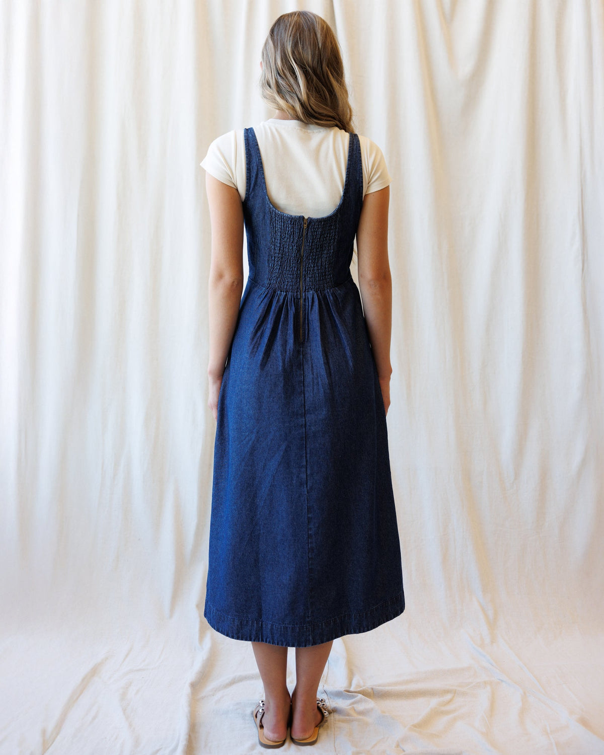 Back view denim dress with smocked waist and adjustable straps
