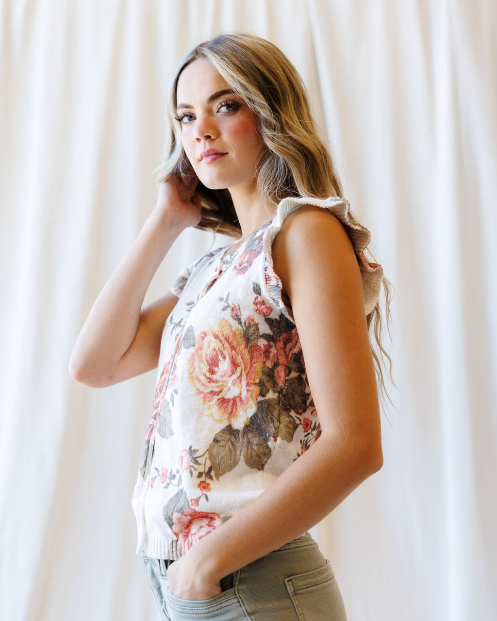Cream floral sleeveless cardigan with button placket and ruffled shoulder trim