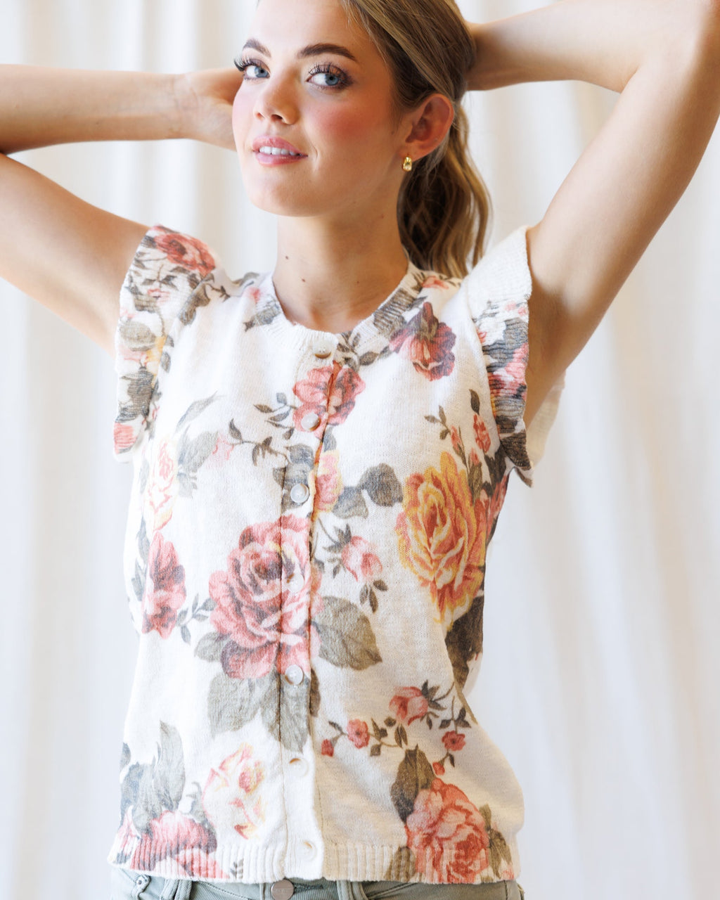 Cream floral sleeveless cardigan with front buttons and fitted ribbed waist hem