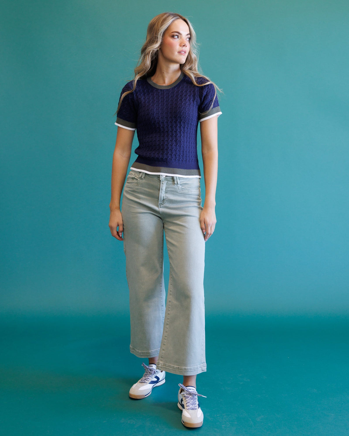 Dark blue cable-knit crewneck sweater with short sleeves, stripe trim, and ribbed hem