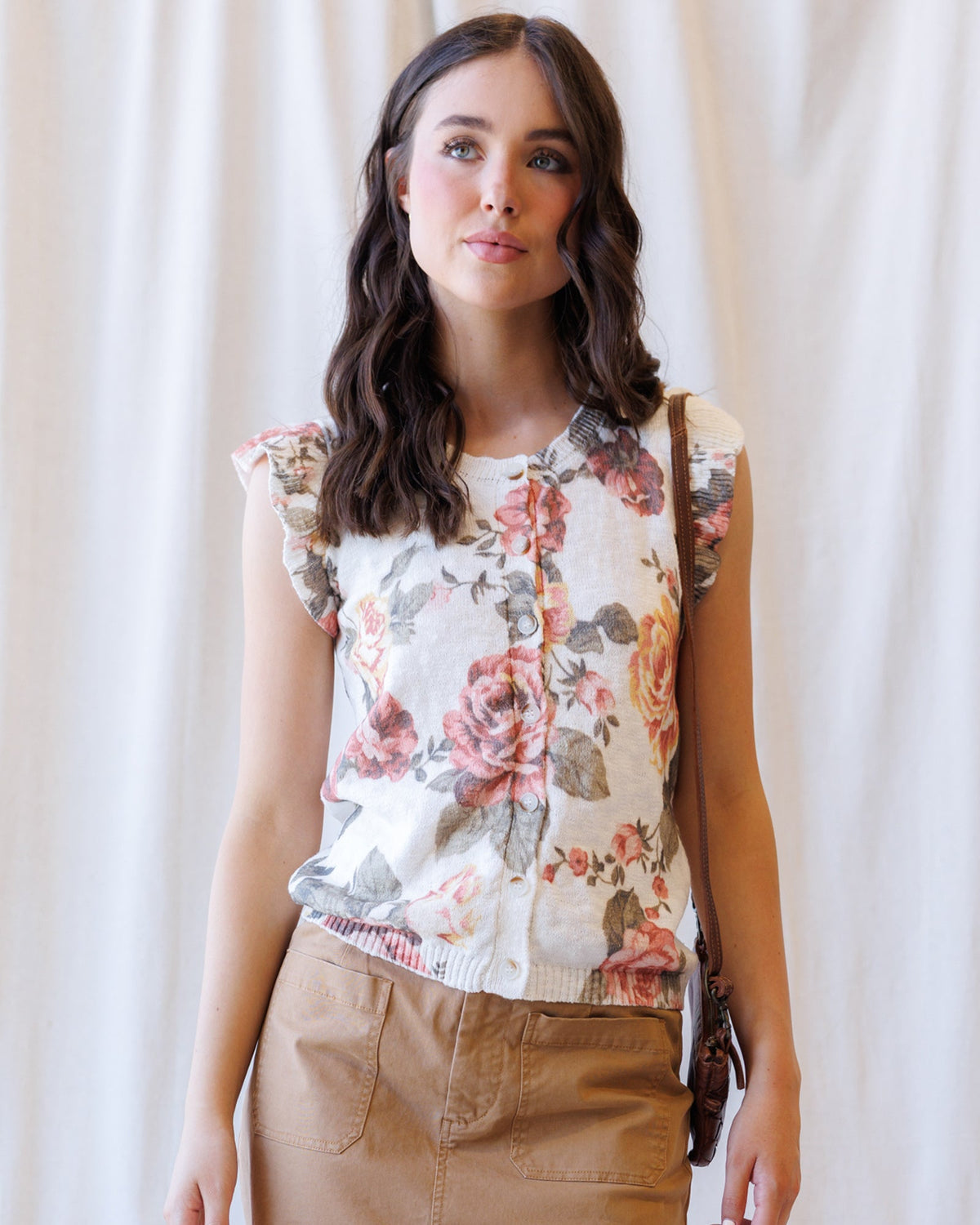 Cream floral sleeveless cardigan with button front and ribbed hem with ruffle trim