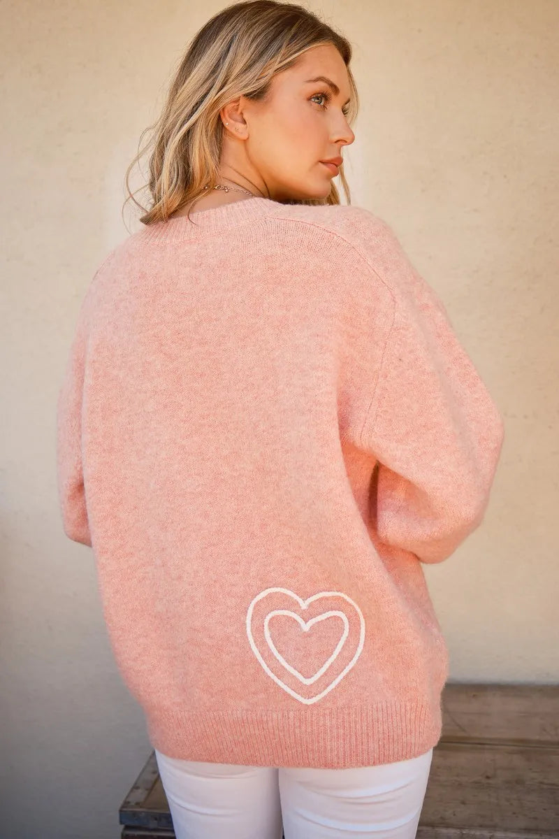Pink round-neck sweater with heart outline graphic on the back
