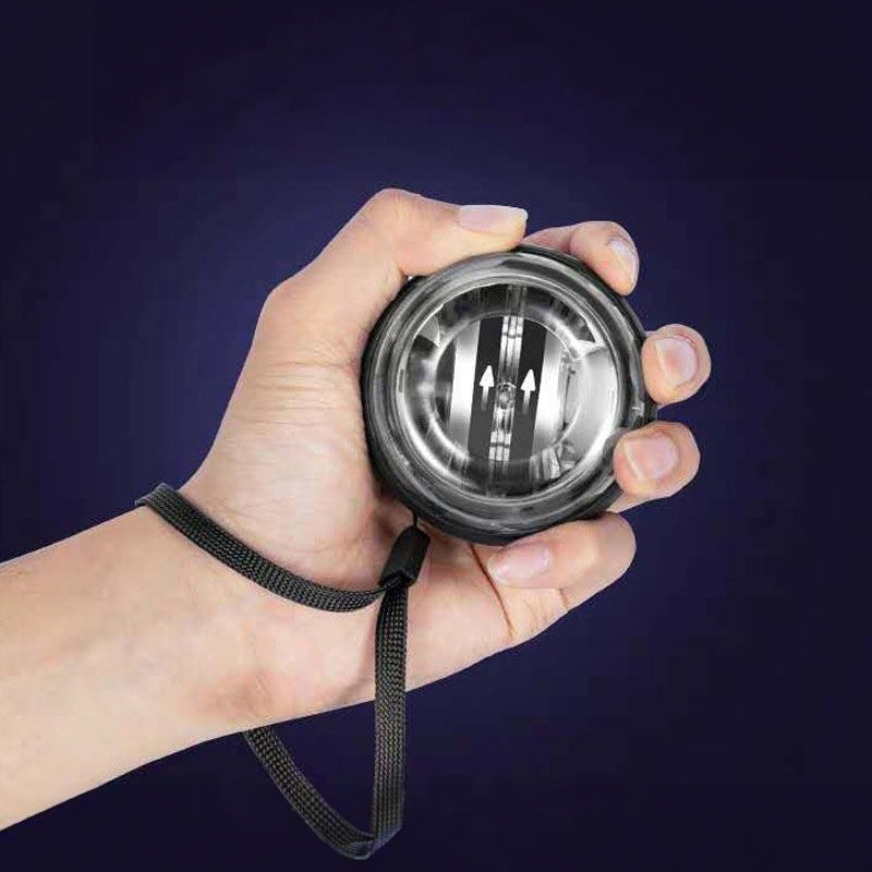 Hand holding a circular wrist gyro ball exerciser with strap and clear core housing
