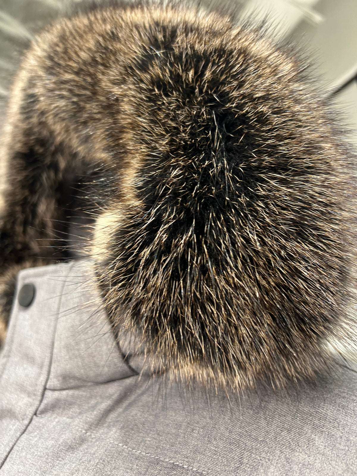 Close-up of dark brown fur hood trim on a grey puffer coat
